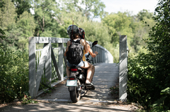 Bild zeigt zwei Leute auf einem E-Moped über eine Brücke fahren