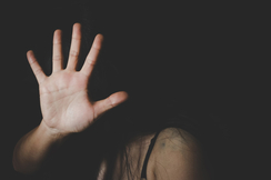 Das Bild zeigt eine Frau, die ihre Hand vor ihr Gesicht hält, was eine Abwehrhaltung signalisiert.