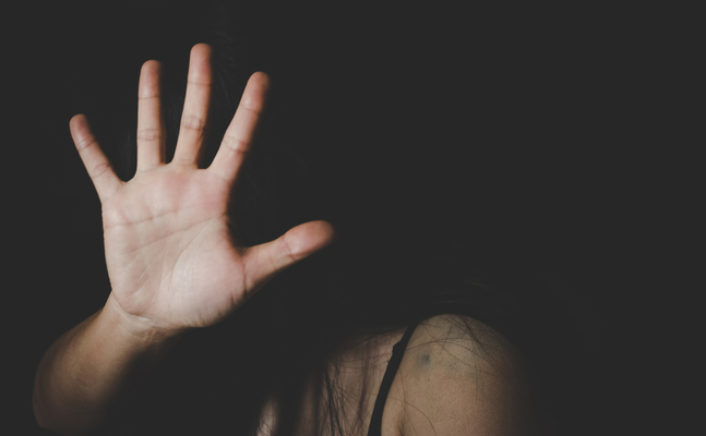 Das Bild zeigt eine Frau, die ihre Hand vor ihr Gesicht hält, was eine Abwehrhaltung signalisiert.